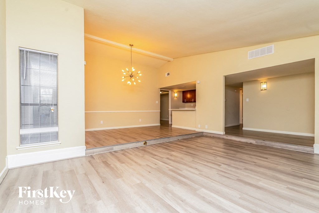 A large empty room with wooden floors and a chandelier hanging from the ceiling.