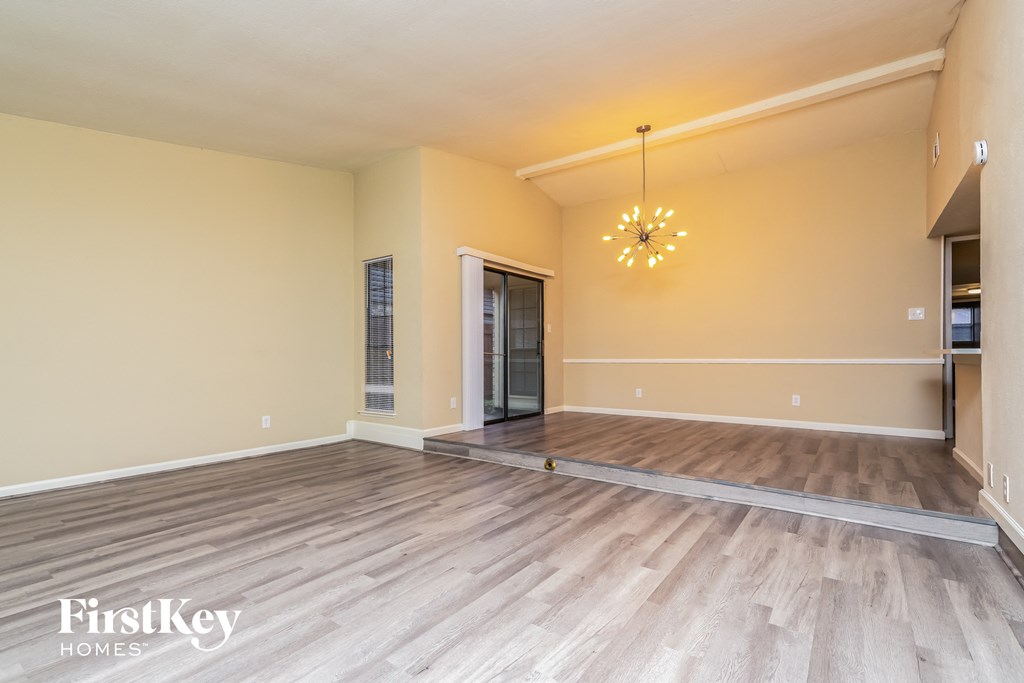 A spacious room with wooden flooring and a chandelier hanging from the ceiling.