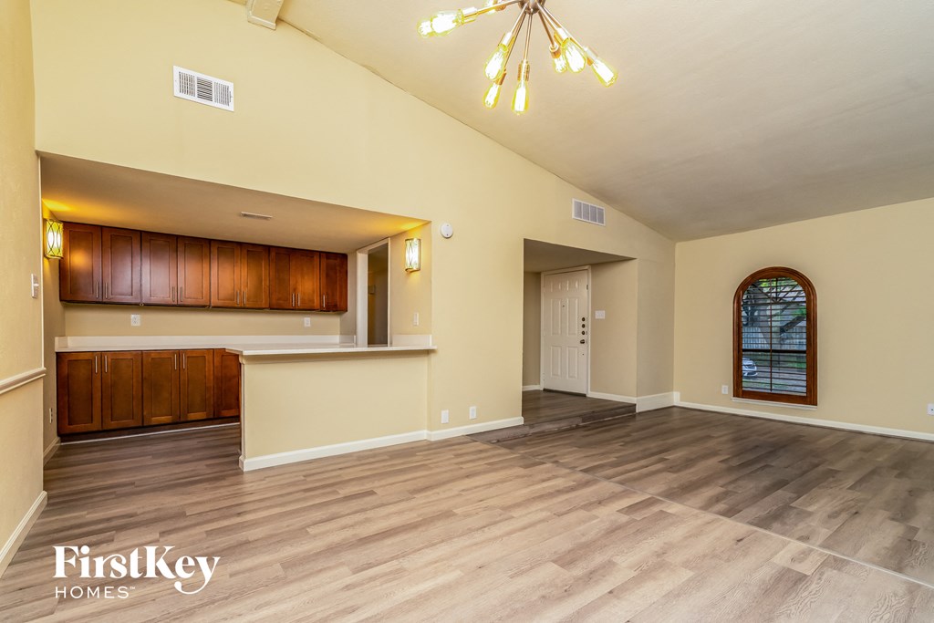 A spacious room with wooden flooring and a large window.