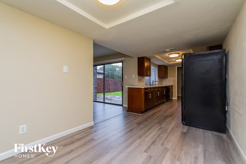 A kitchen area with a black refrigerator and wooden floors.