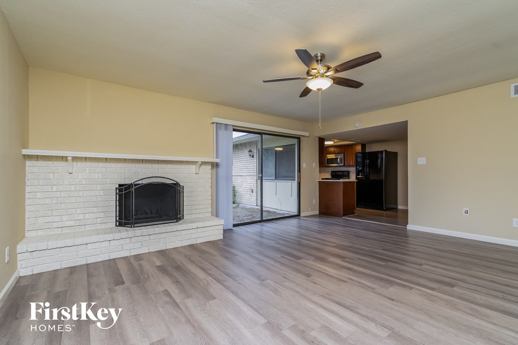 A living room with a fireplace and a ceiling fan.