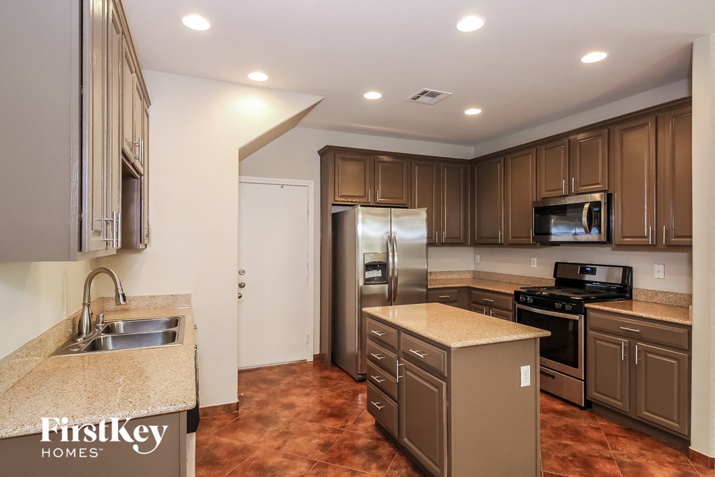 A kitchen with brown cabinets and a granite countertop.