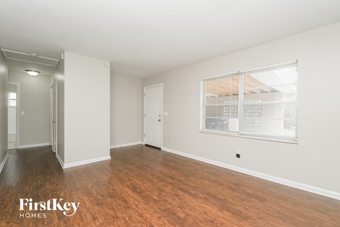 A room with wooden floors and a window with blinds.