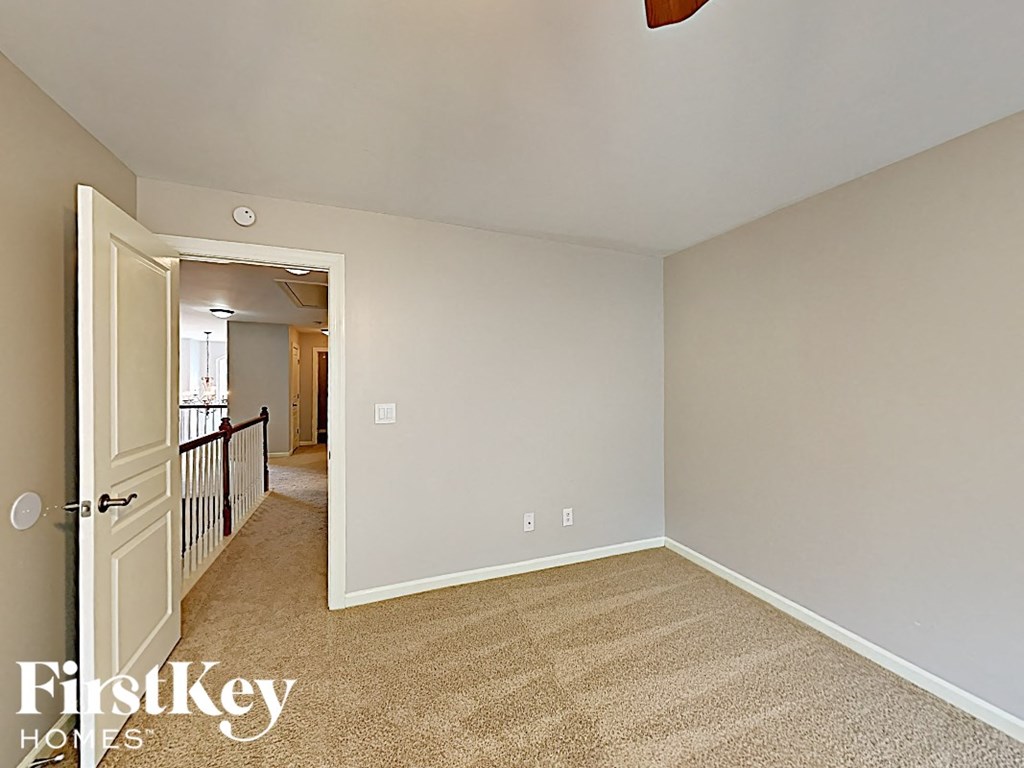a bedroom with a door to the hallway and carpeted flooring