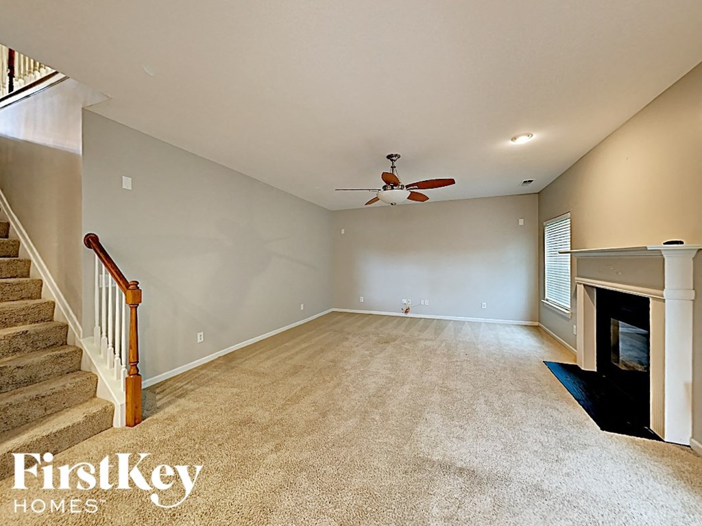 a empty living room with a fireplace and a ceiling fan