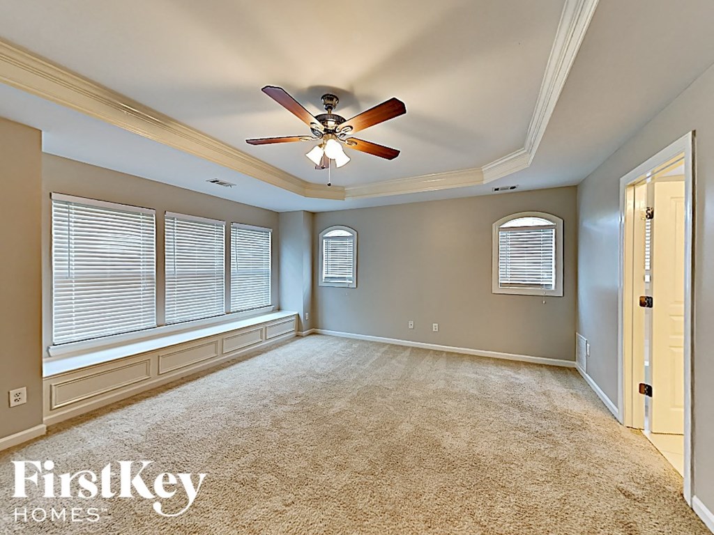 an empty living room with a ceiling fan and a large window