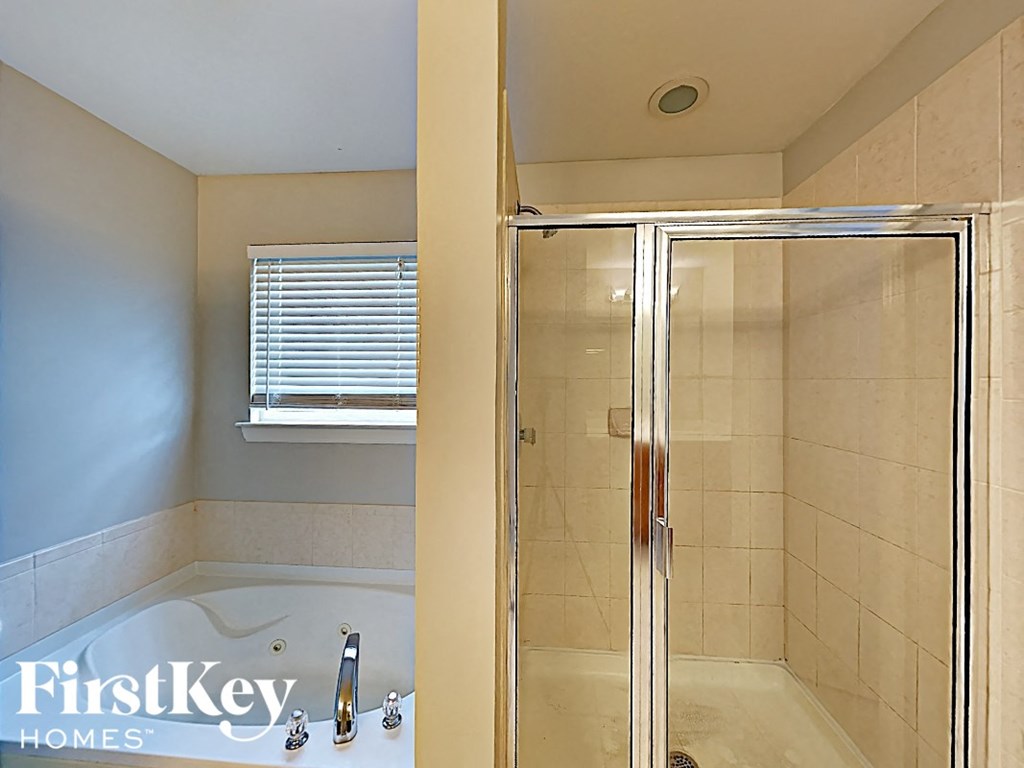 a bathroom with a shower and a tub and a window