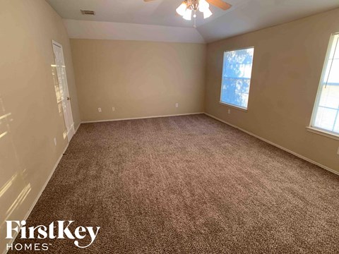 a carpeted living room with a window and a ceiling fan