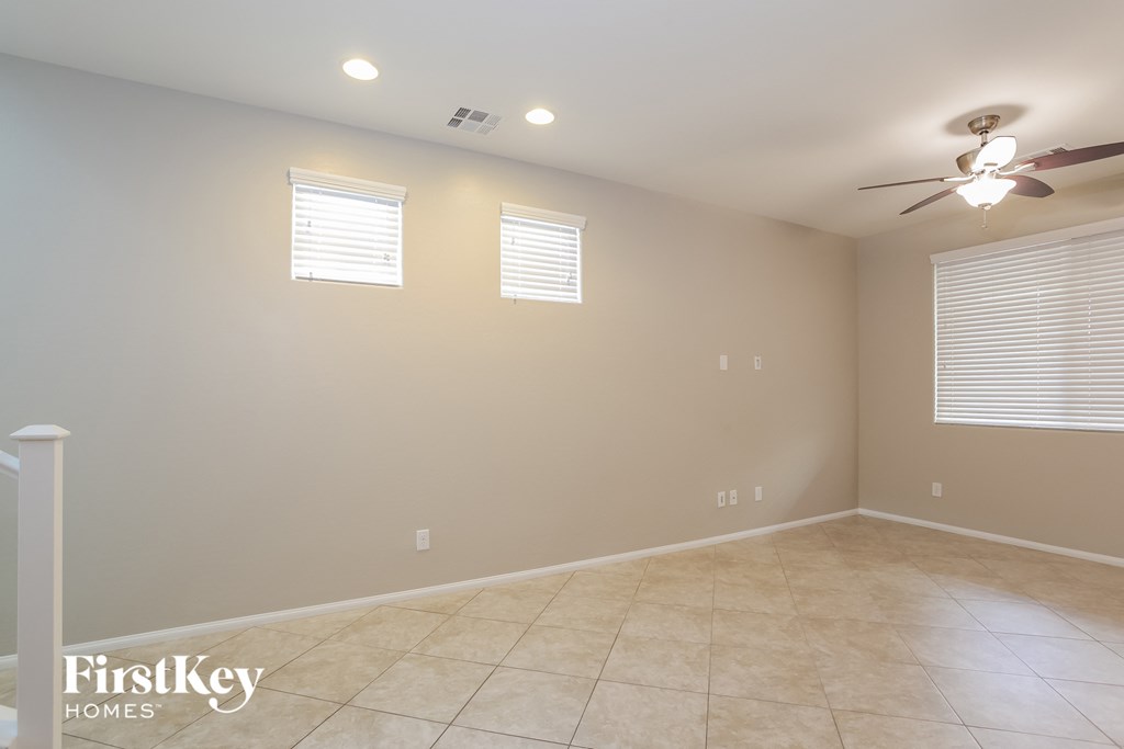 A room with a fan and two windows.