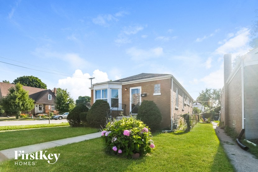 a brick house with a lawn and flowers in front of it