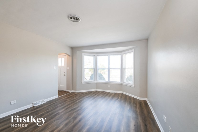 the living room of an empty house with wood flooring and a large window