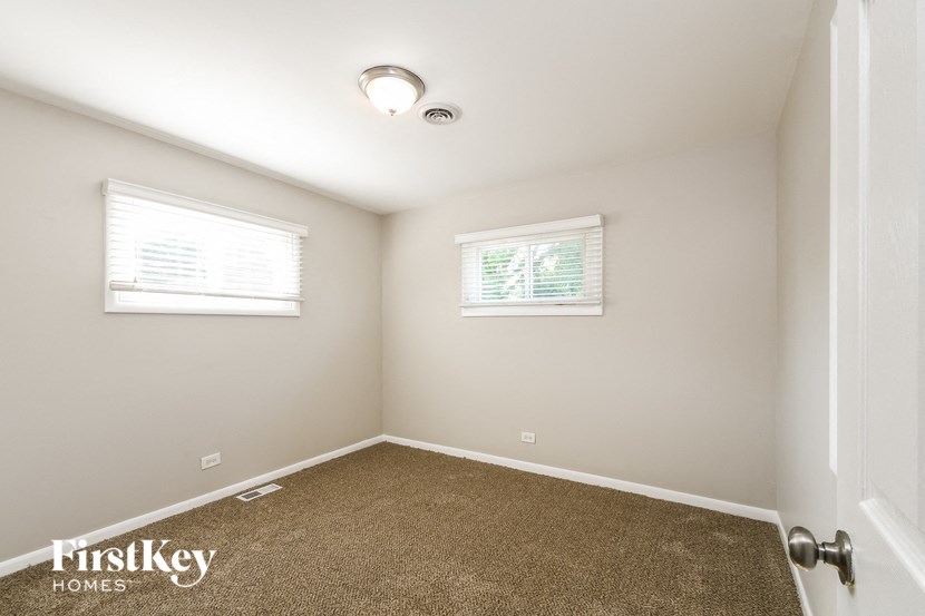 a bedroom with a carpeted floor and two windows