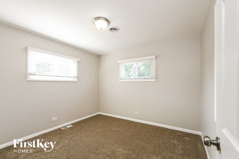 a bedroom with a carpeted floor and two windows