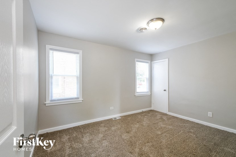 a bedroom with two windows and a carpeted floor