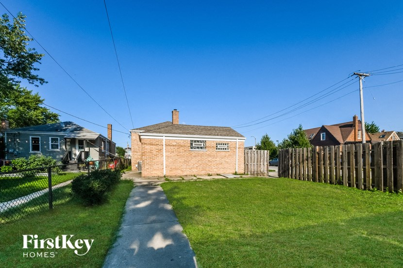 a small brick house with a yard and a wooden fence