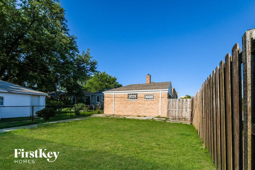a backyard with a brick house and a wooden fence