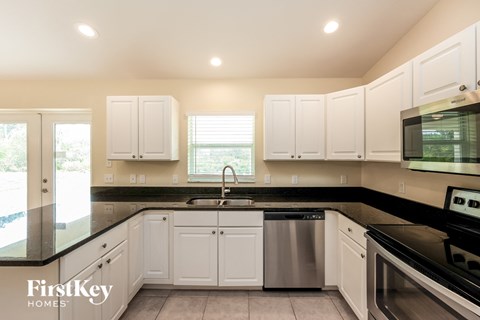 a kitchen with white cabinets and black counter tops