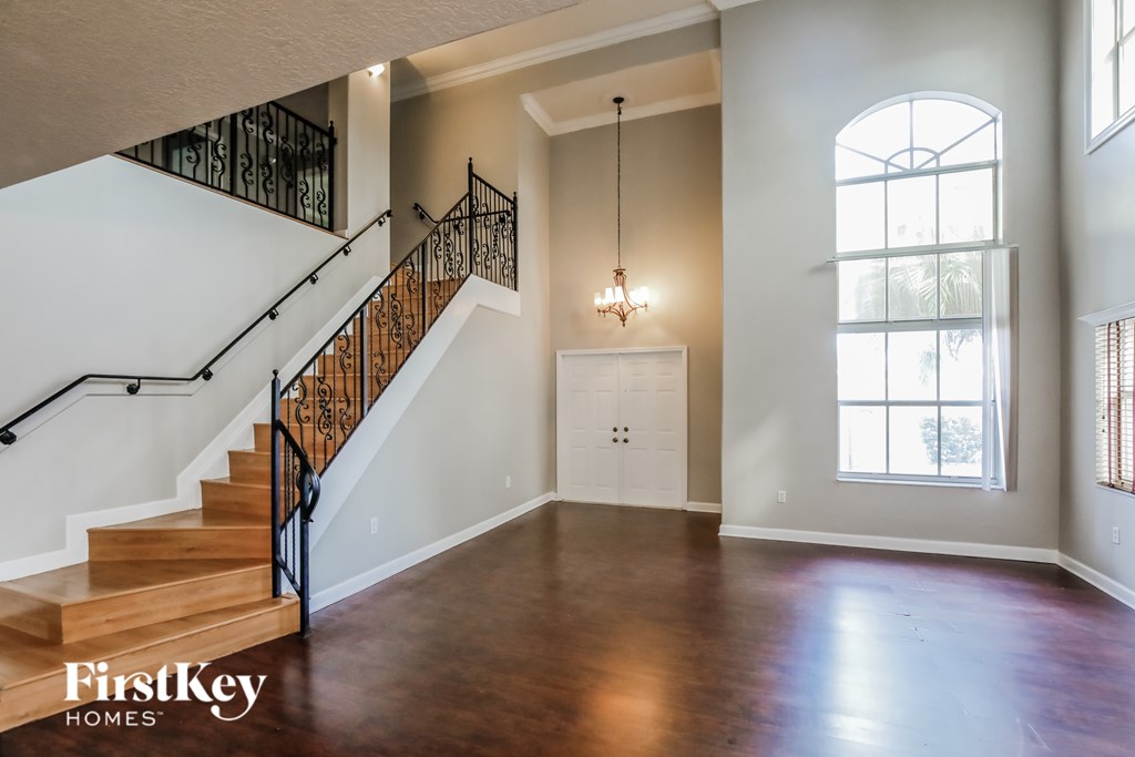 A spacious room with a staircase and a chandelier.