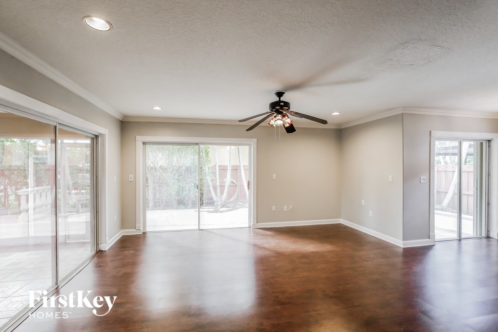 A spacious room with a ceiling fan and sliding glass doors.