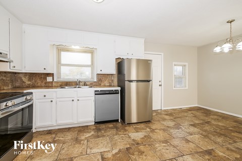 A kitchen with a stove top oven, a dishwasher, and a refrigerator.