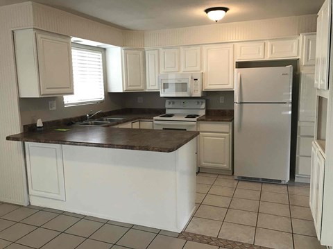 A kitchen with white cabinets and a brown countertop.