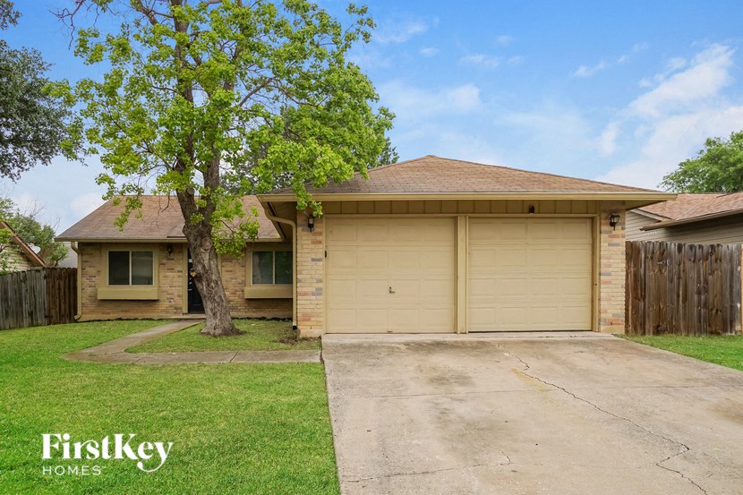 a yellow house with a garage door and a tree