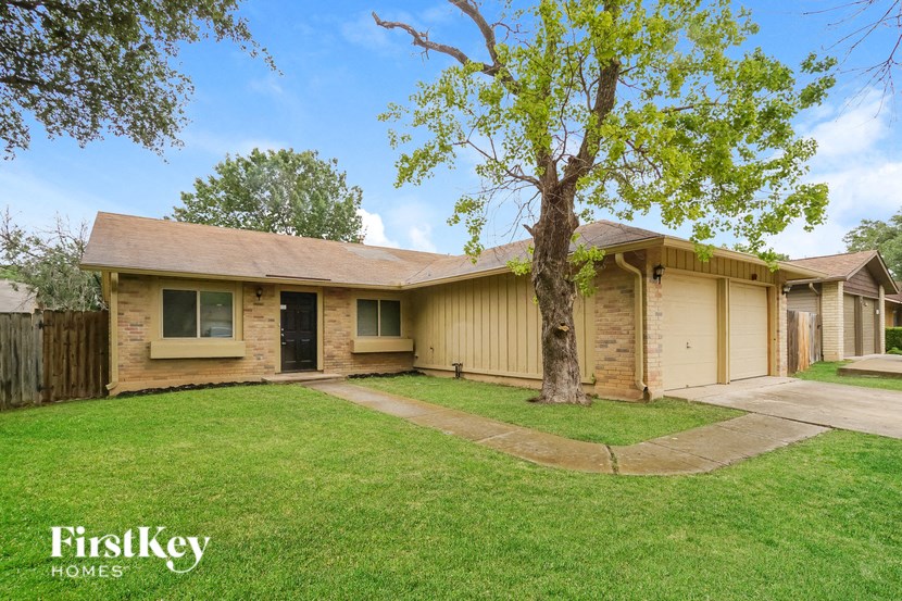 a tan brick house with a tree in the yard