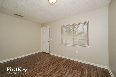the living room of a home with a wooden floor and a window