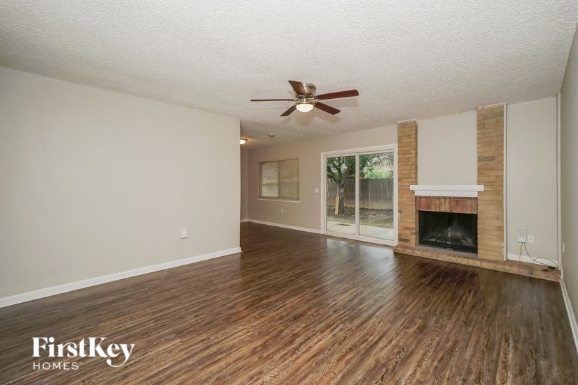 an empty living room with a fireplace and a ceiling fan