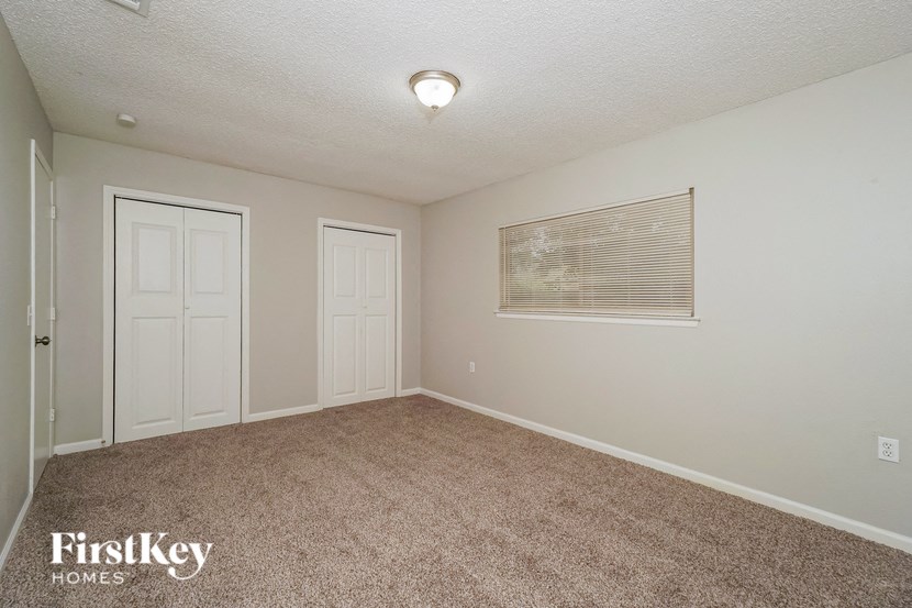 a room with a carpeted floor and two doors and a window