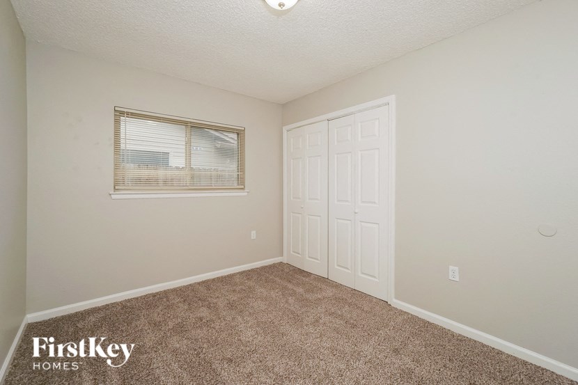 the bedroom of a home with a white door and a window