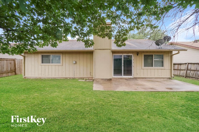a small tan house with a yard and a patio
