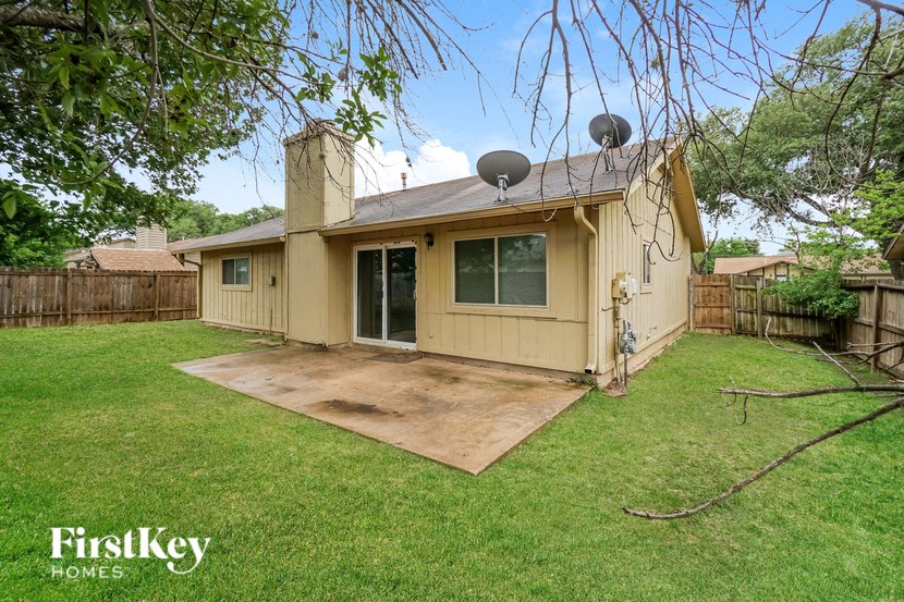 a small yellow house with a yard and a patio