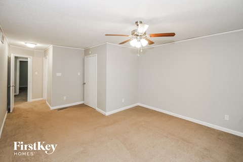 a living room with carpet and a ceiling fan
