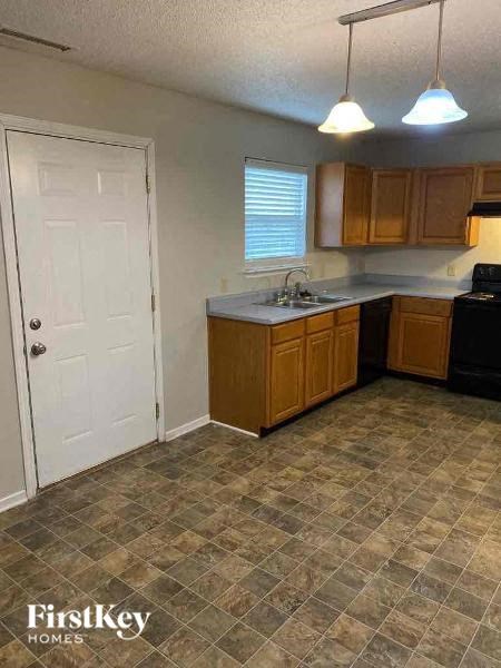 A kitchen with a tile floor and wooden cabinets.