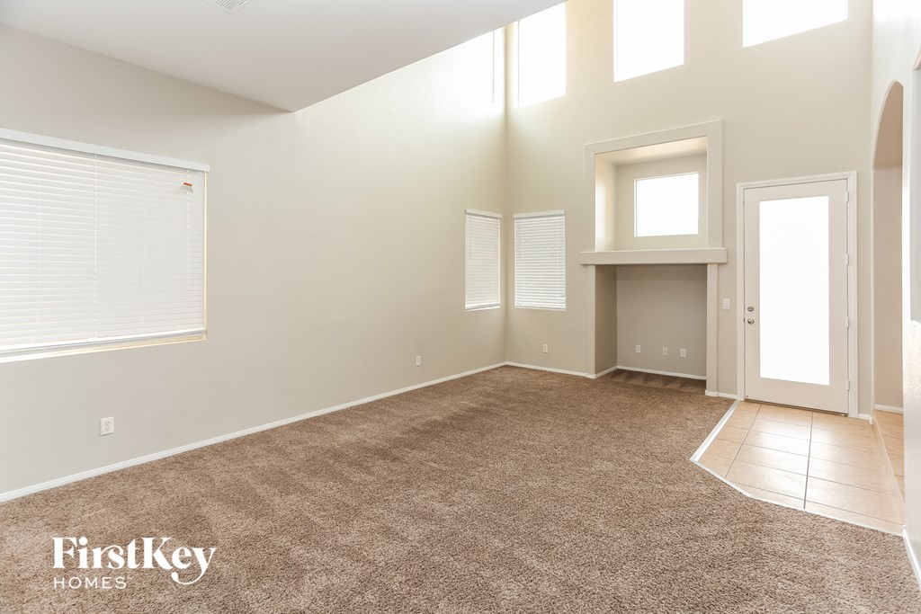 A spacious room with a carpeted floor and a door on the right side.