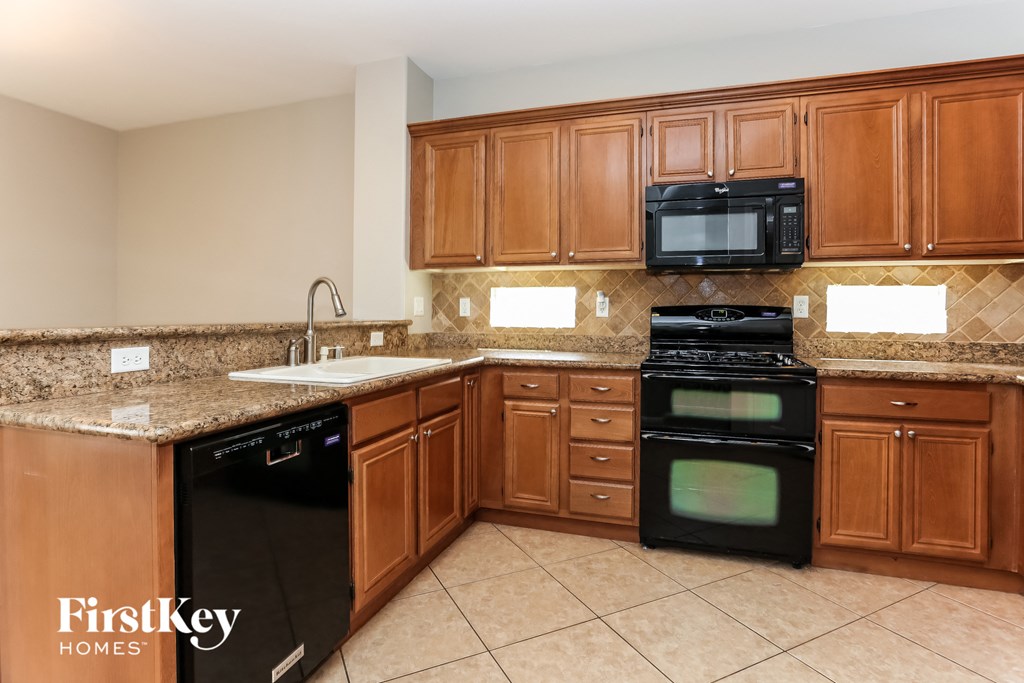 A kitchen with brown cabinets and a black dishwasher.