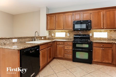 A kitchen with brown cabinets and a black dishwasher.