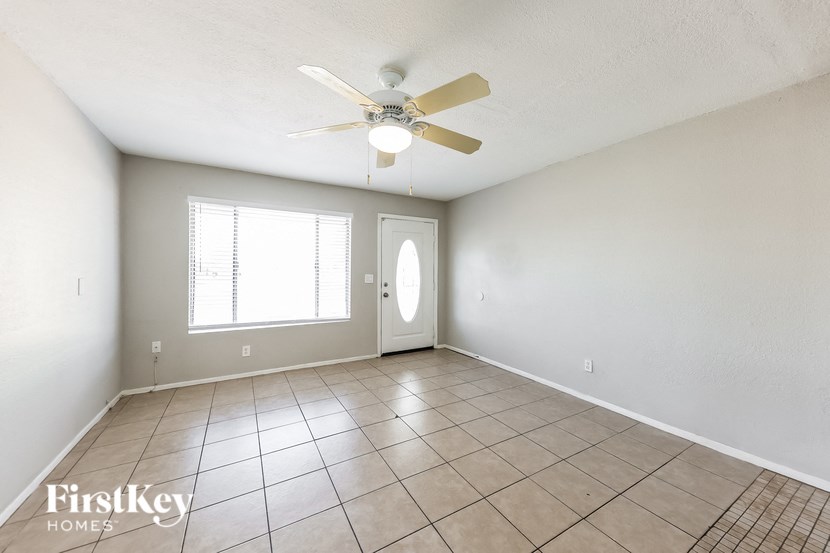 A room with a fan, tile floor, and a window.