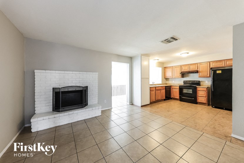 A living room with a fireplace and a kitchen area in the background.