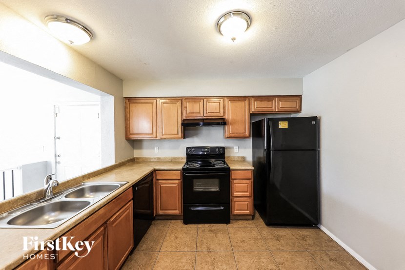 A kitchen with wooden cabinets and black appliances.