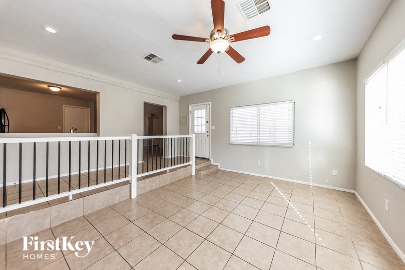 A spacious room with a ceiling fan and tiled flooring.