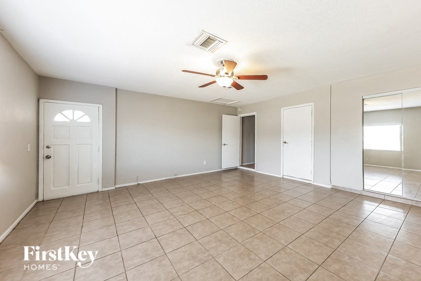 A spacious room with a ceiling fan and tiled flooring.