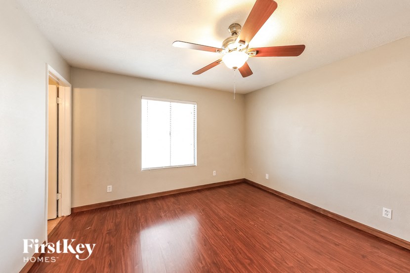 A room with a ceiling fan and wooden flooring.