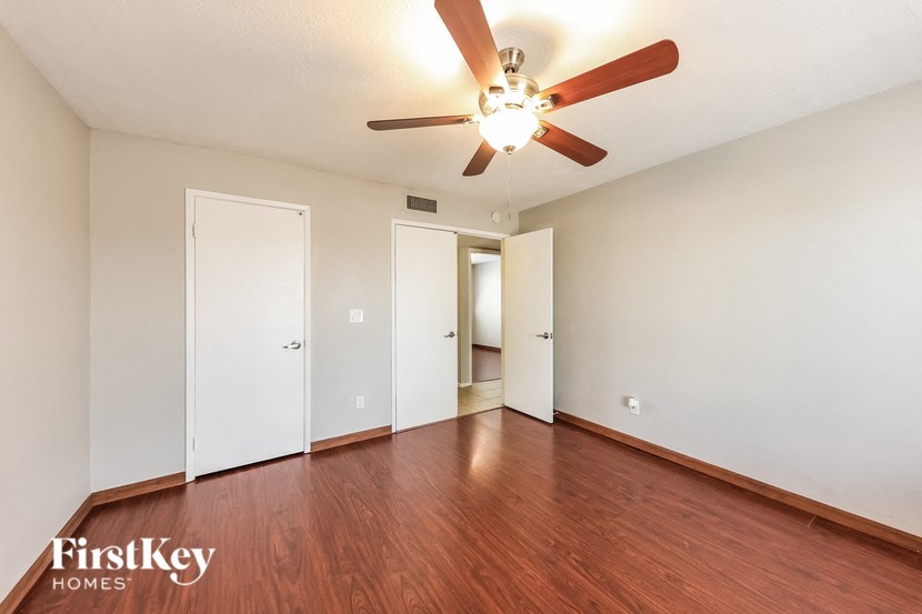 A room with a ceiling fan and wooden floors.