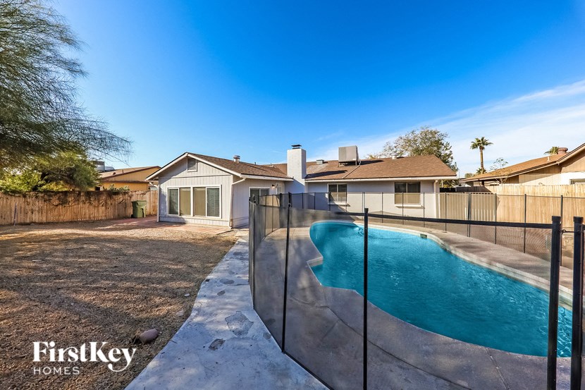A pool in a backyard with a house and a fence.