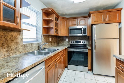 A kitchen with wooden cabinets and a stainless steel refrigerator.