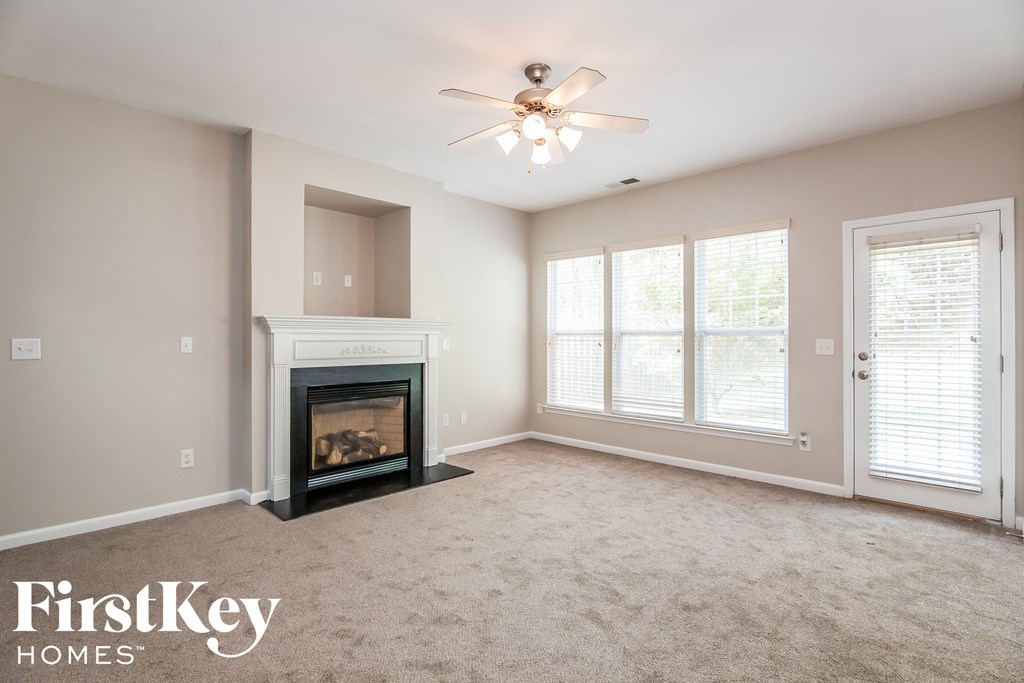 A spacious living room with a fireplace and a ceiling fan.