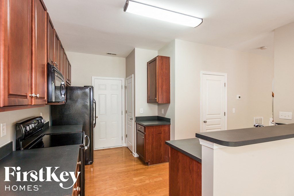 A kitchen with wooden cabinets and a black fridge.