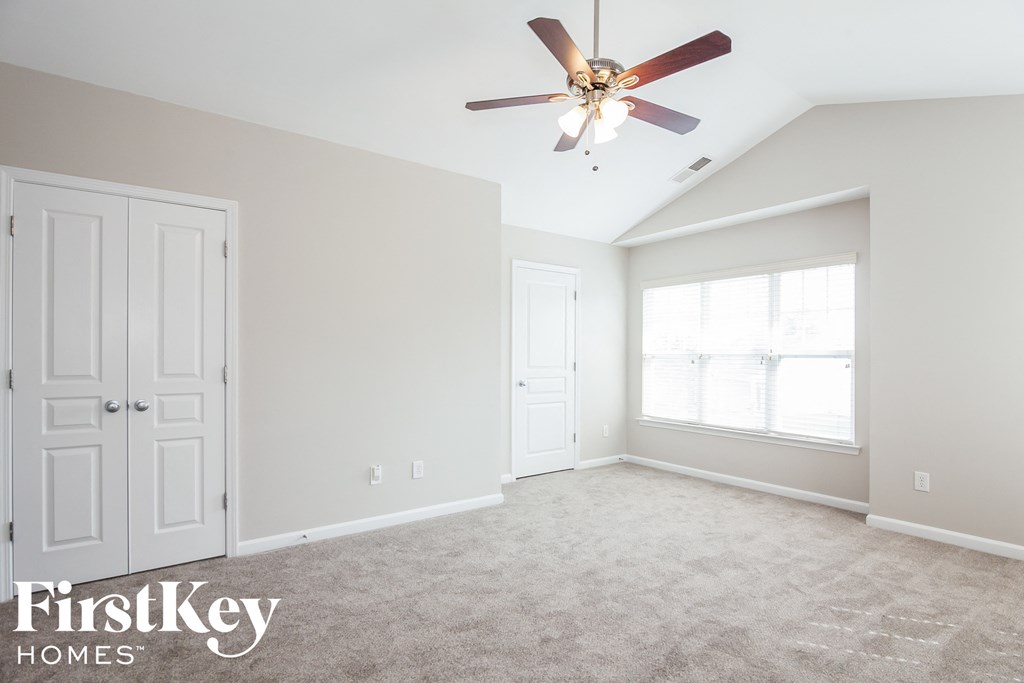 A spacious room with a ceiling fan and two doors.